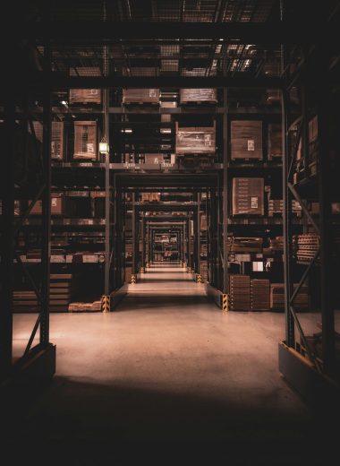 Dimly lit warehouse aisle in Berlin filled with large shelves and boxes, showcasing industrial organization.