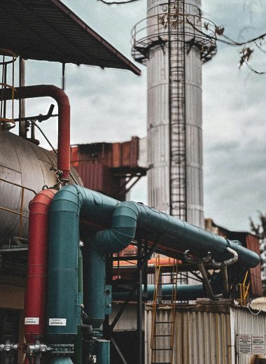View of an industrial facility showcasing colorful pipes and structures under a cloudy sky.